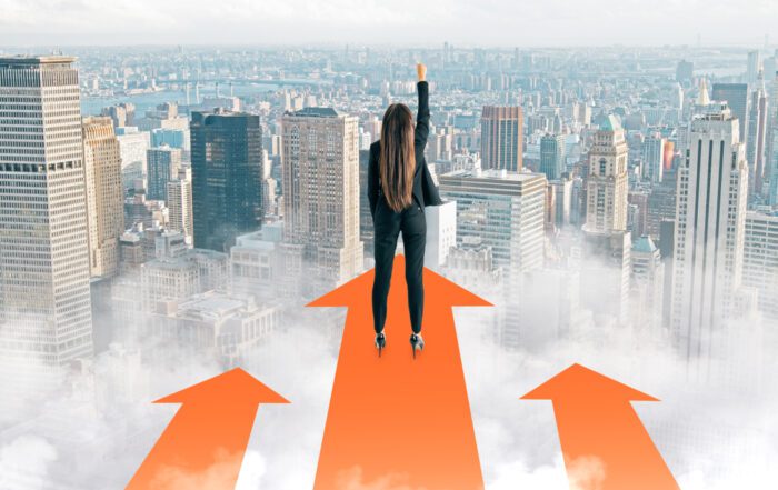 Back view of a young businesswoman with her arm raised, standing on red arrows looking over city buildings, symbolizing the start of a successful trading journey.