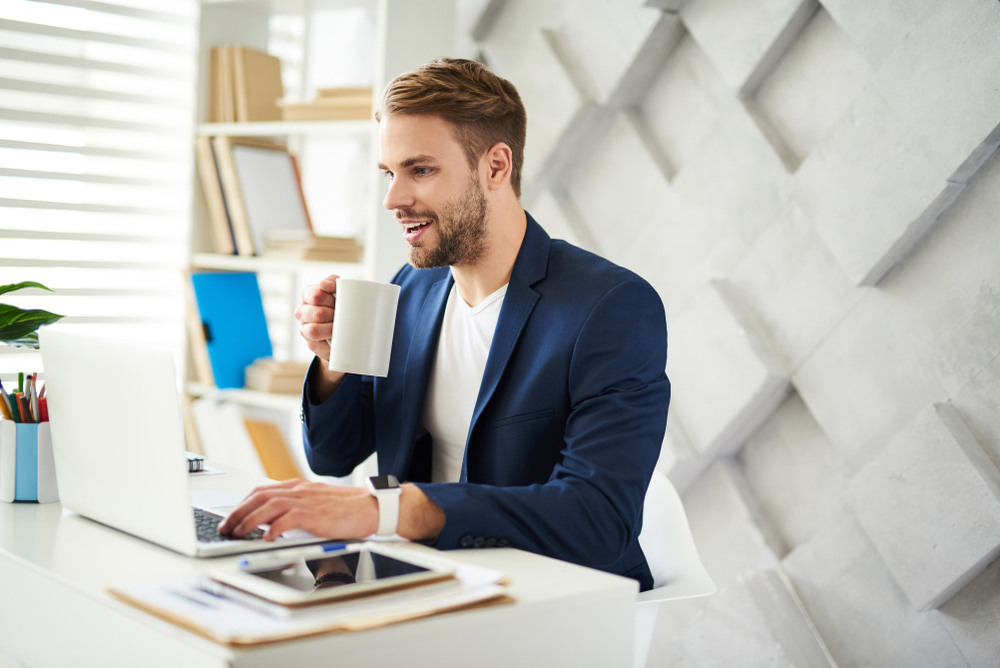 Beleggingsblog – investeerder leest en werkt op laptop met koffie