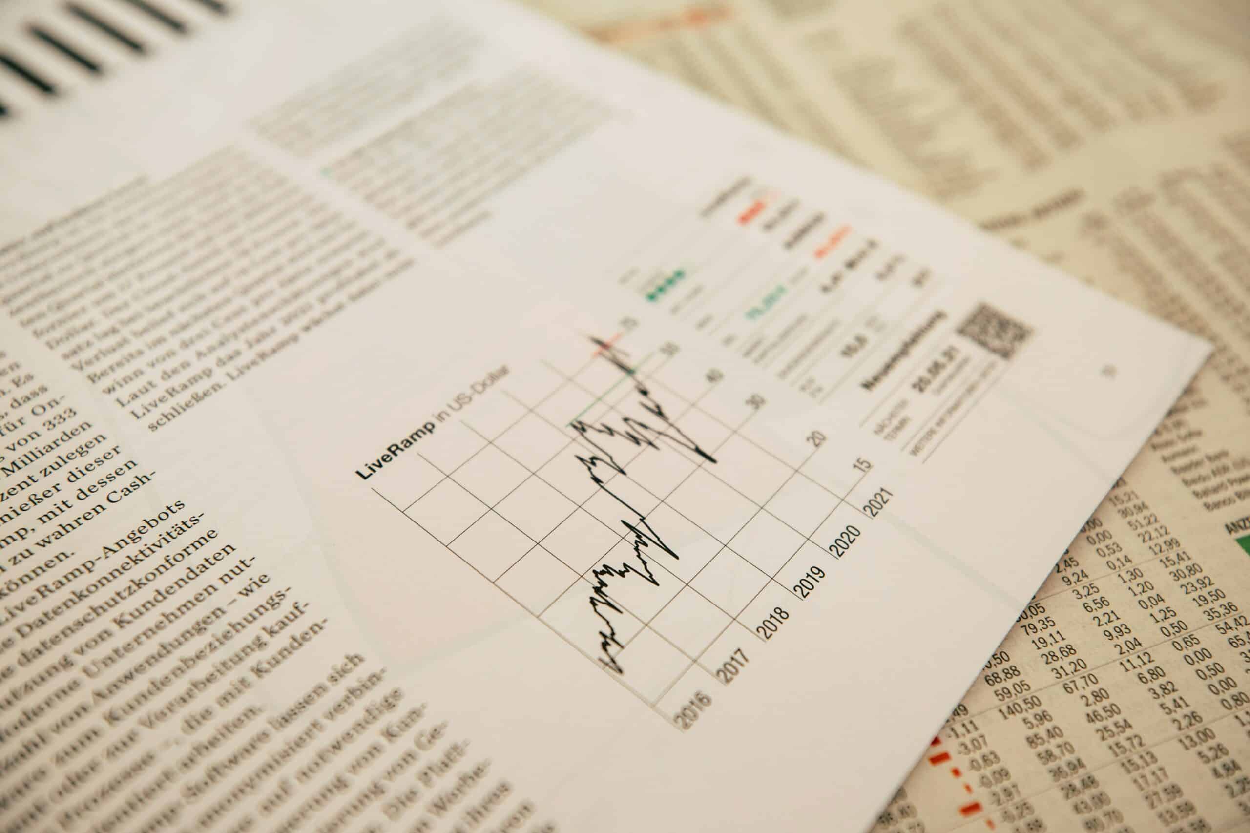 Gestión de cartera: Esta imagen muestra una cotización de acciones en un periódico, superpuesta a los precios de varias acciones.
